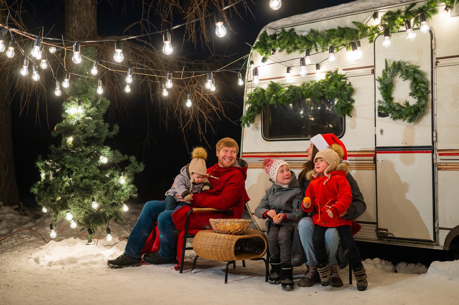 Happy Caucasian family celebrating Christmas outdoors. Parents and three sons travel in a camper.