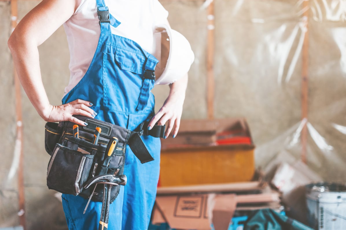 A young woman uses a screwdriver to screw the wood screws into the boards. Home repair, building your own home with your own hands.